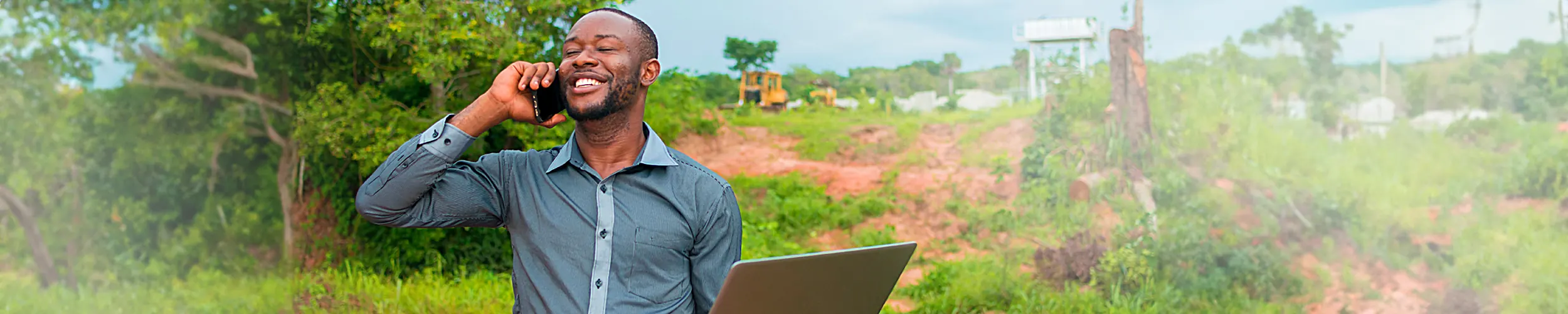 photo of a man on a laptop, talking on the phone outdoors (Green Payroll hero image)