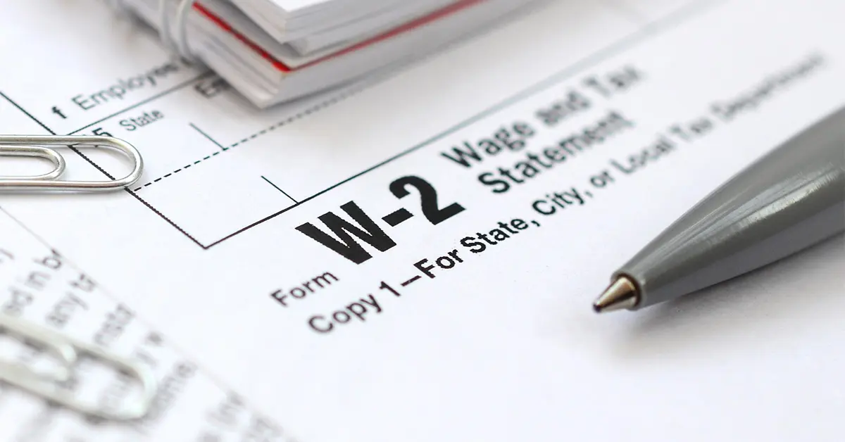 Close-up photo of W2 form with paperclips, notebook and pen resting on top (featured image: "W2 vs W4: Understanding the Key Differences in Common IRS Forms" blog)